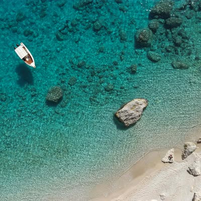 A small boat on clear turquoise water, seen from above