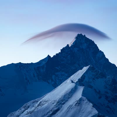 Snow-capped peak beneath a lenticular cloud